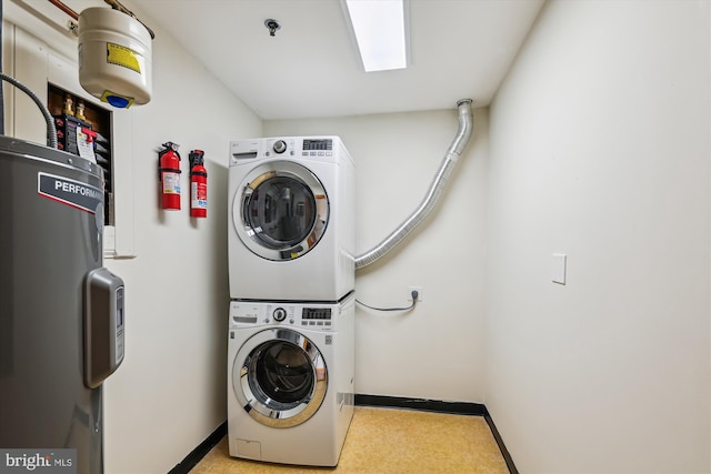 laundry room with water heater, stacked washer / dryer, and baseboards