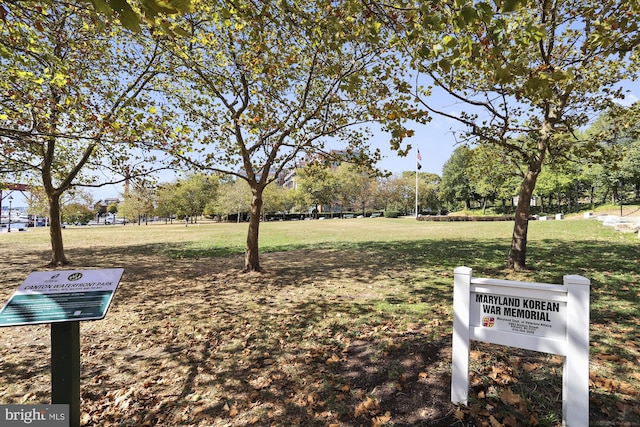 surrounding community with a lawn and view of wooded area
