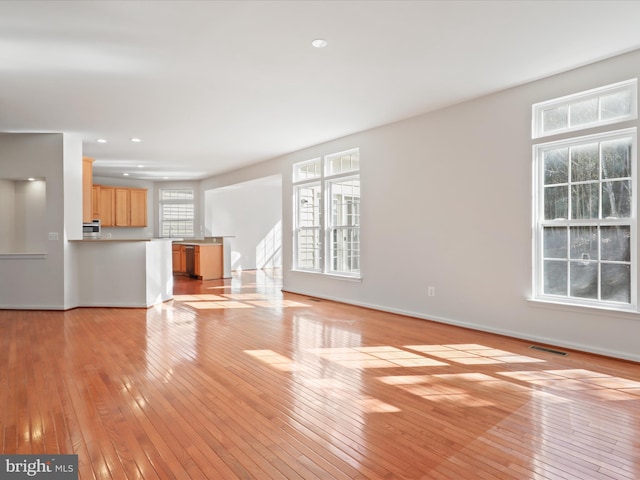 unfurnished living room with light wood finished floors, baseboards, and recessed lighting
