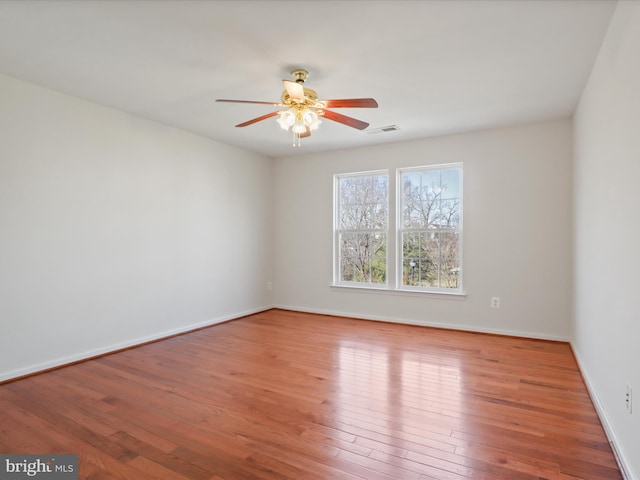 unfurnished room featuring a ceiling fan, wood finished floors, and baseboards