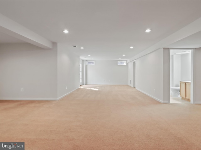 finished below grade area featuring light colored carpet, recessed lighting, and baseboards