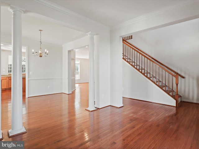 unfurnished living room with wood-type flooring, ornamental molding, stairs, a chandelier, and decorative columns