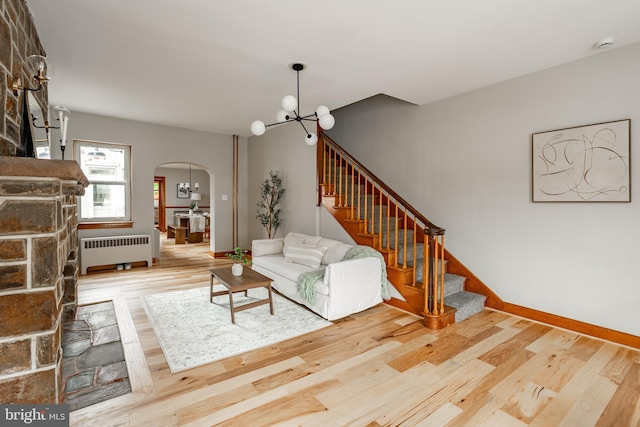 308 Cherry St, Columbia, PA 17512 - living area with radiator heating unit, arched walkways, a chandelier, stairway, and wood finished floors