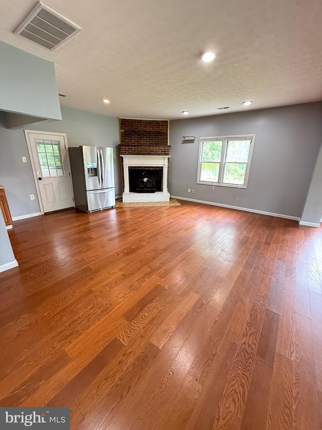 7421 Lake Dr, Manassas, VA 20111 - unfurnished living room featuring baseboards, plenty of natural light, wood finished floors, a brick fireplace, and recessed lighting
