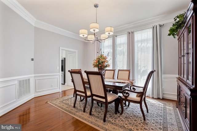 42743 Macauley Pl, Ashburn, VA 20148 - dining room with a chandelier, ornamental molding, wood finished floors, a wainscoted wall, and a decorative wall