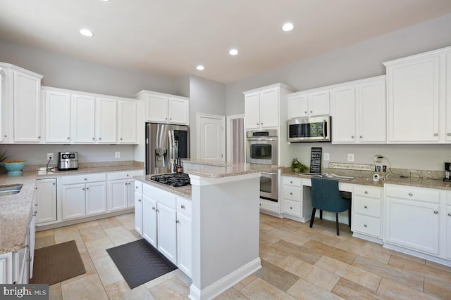 42743 Macauley Pl, Ashburn, VA 20148 - kitchen featuring appliances with stainless steel finishes, white cabinetry, a kitchen island, light stone countertops, and recessed lighting