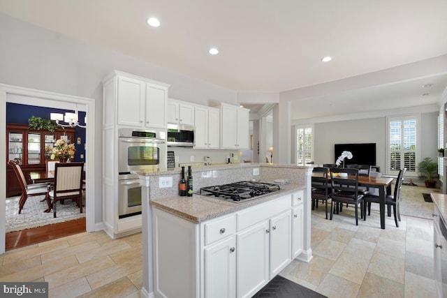 42743 Macauley Pl, Ashburn, VA 20148 - kitchen featuring stainless steel appliances, open floor plan, a center island, white cabinets, and a chandelier