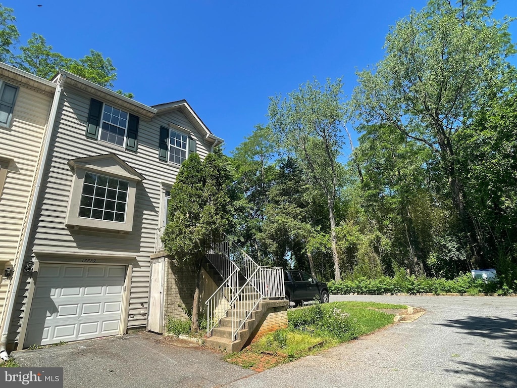view of front of home featuring driveway, a garage, and stairs