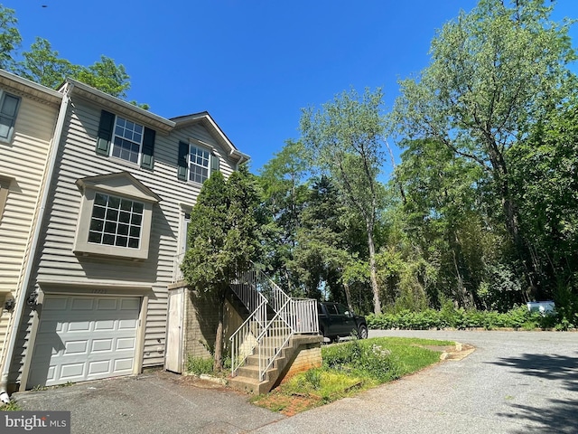 view of front of home featuring driveway, a garage, and stairs