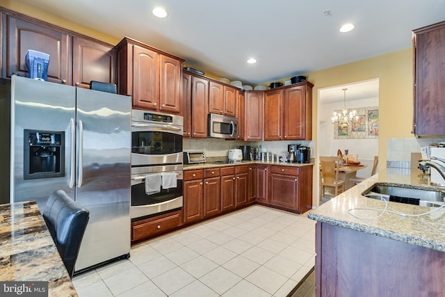 15603 Chadsey Ln, Brandywine, MD 20613 - kitchen featuring appliances with stainless steel finishes, a sink, a chandelier, backsplash, and light stone counters