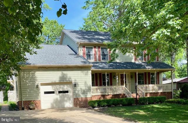 view of front facade with a garage, a porch, driveway, and a front lawn