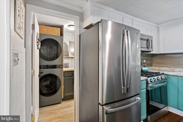 272 Main St, Hamilton, NJ 08620 - kitchen featuring appliances with stainless steel finishes, estacked washer and dryer, crown molding, white cabinetry, and light countertops