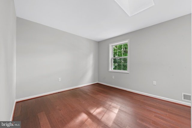 unfurnished room featuring wood finished floors, baseboards, and a skylight