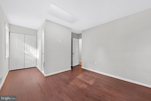 unfurnished bedroom featuring wood finished floors, baseboards, and a closet