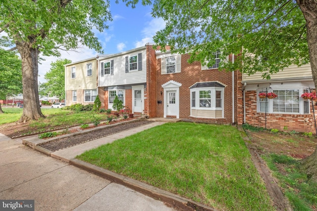 view of property featuring a front yard and brick siding