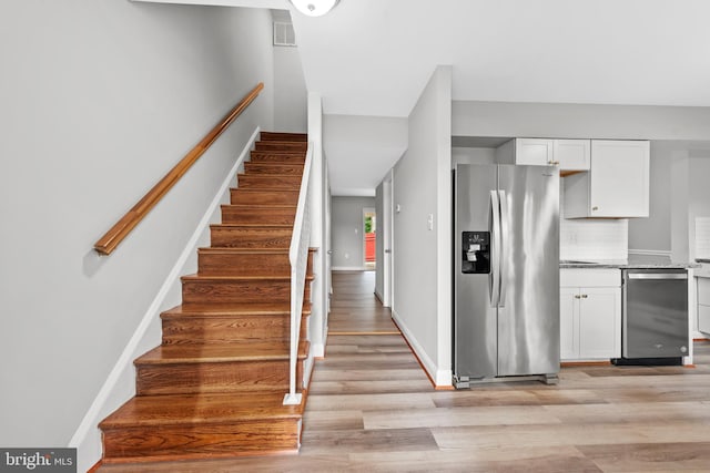 stairway with wood finished floors and baseboards