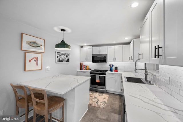 1505 Wynnewood Rd, Ardmore, PA 19003 - kitchen with gas range, backsplash, white cabinetry, light stone countertops, and a breakfast bar