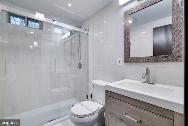 bathroom with tile walls, toilet, a shower stall, vanity, and decorative backsplash
