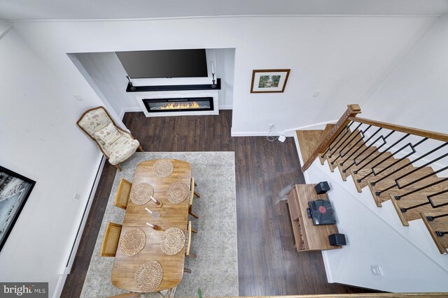 living room with wood finished floors, stairway, baseboards, and a glass covered fireplace