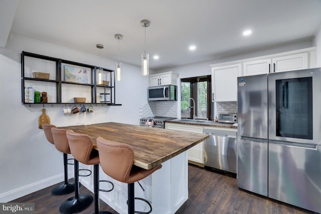 kitchen with stainless steel appliances, a sink, decorative backsplash, white cabinets, and recessed lighting
