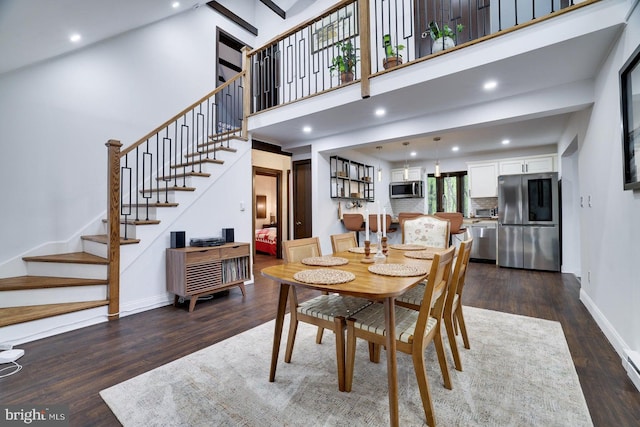 dining room with stairs, dark wood-style floors, baseboards, recessed lighting, and a high ceiling