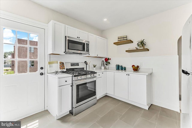 564 9th Ave, Prospect Park, PA 19076 - kitchen featuring appliances with stainless steel finishes, light countertops, open shelves, white cabinetry, and arched walkways