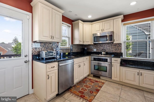 806 S Beechfield Ave, Baltimore, MD 21229 - kitchen with stainless steel appliances, cream cabinetry, a sink, decorative backsplash, and recessed lighting