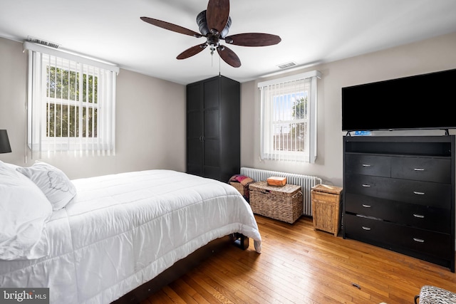 806 S Beechfield Ave, Baltimore, MD 21229 - bedroom with light wood-type flooring, multiple windows, radiator heating unit, and a ceiling fan