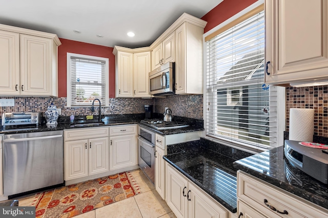 806 S Beechfield Ave, Baltimore, MD 21229 - kitchen with stainless steel appliances, a sink, decorative backsplash, light tile patterned flooring, and dark stone counters