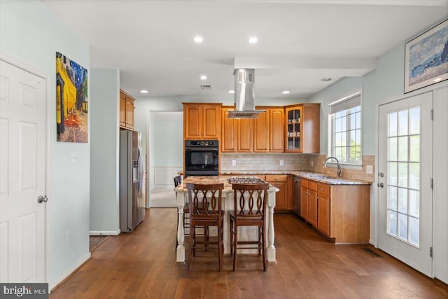 313 Indianhead Ct, Woodstock, VA 22664 - kitchen with appliances with stainless steel finishes, island exhaust hood, brown cabinetry, a sink, and light stone counters
