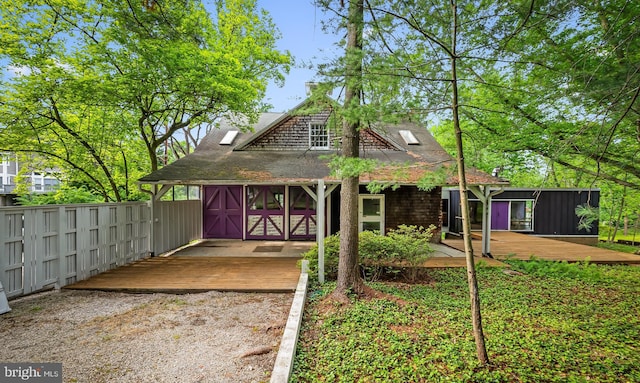 view of front of house featuring a wooden deck and roof with shingles