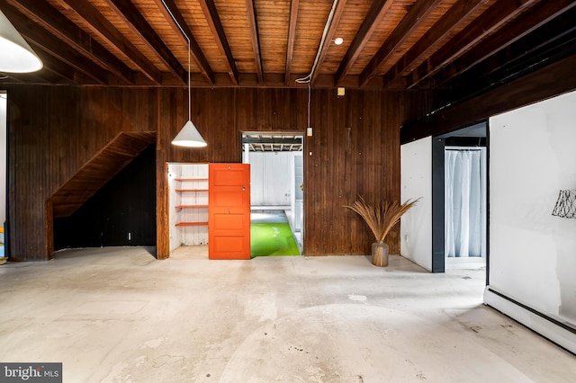 miscellaneous room with wooden walls, baseboard heating, and concrete flooring