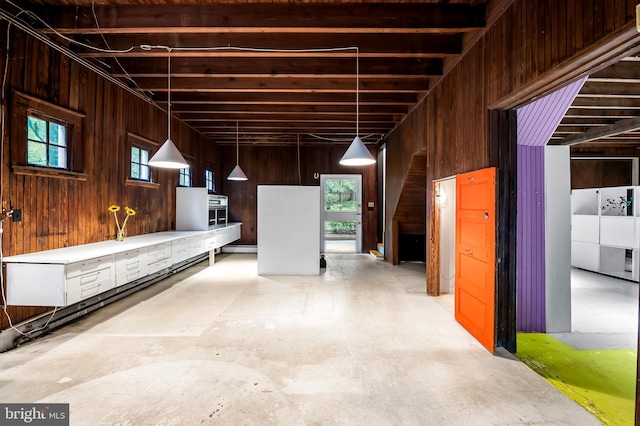 misc room featuring unfinished concrete flooring, wood walls, and baseboard heating