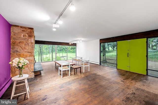 dining room with track lighting, wood-type flooring, and a baseboard heating unit