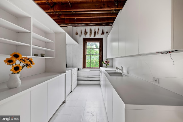 kitchen with independent washer and dryer, a sink, white cabinets, light countertops, and open shelves