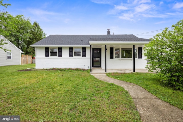 single story home featuring brick siding, a front yard, a chimney, and a shingled roof