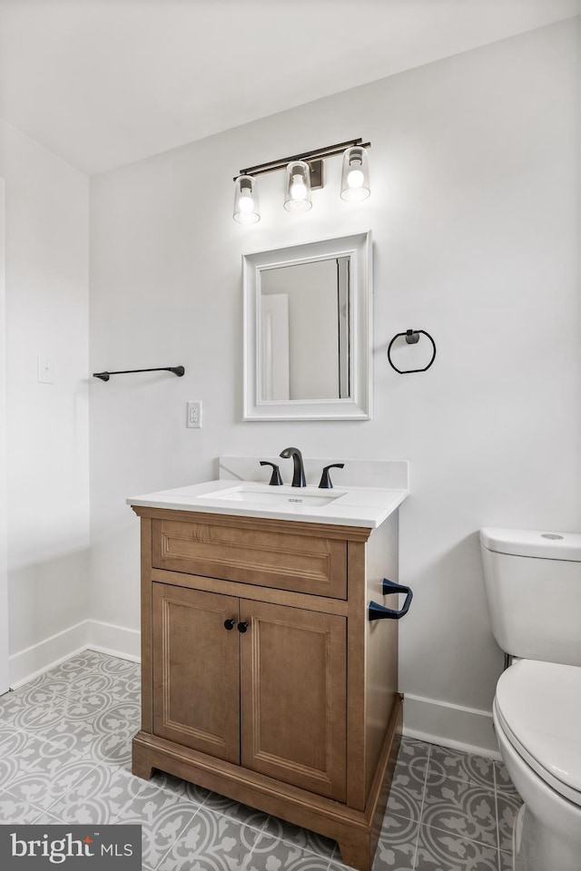 bathroom with baseboards, vanity, and toilet