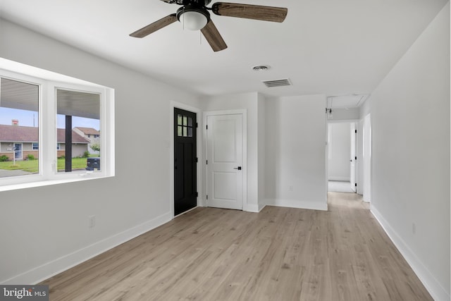 unfurnished room with attic access, light wood finished floors, ceiling fan, and baseboards