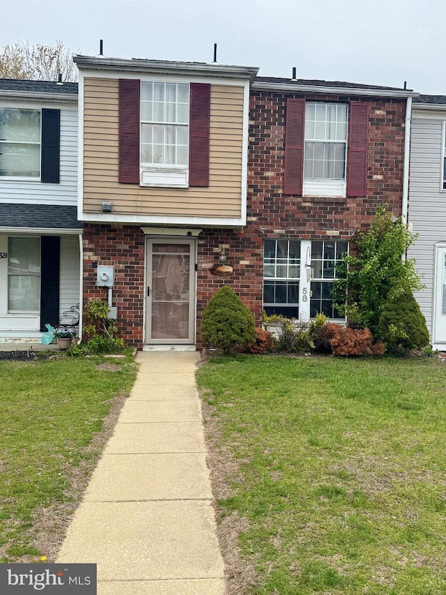 townhome / multi-family property featuring a front yard and brick siding