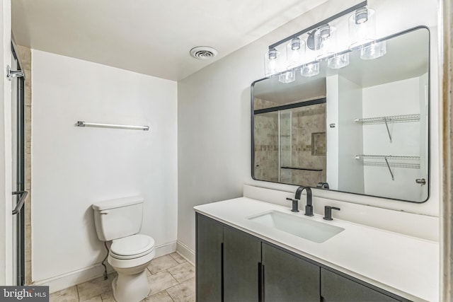 bathroom with toilet, baseboards, a tile shower, and vanity