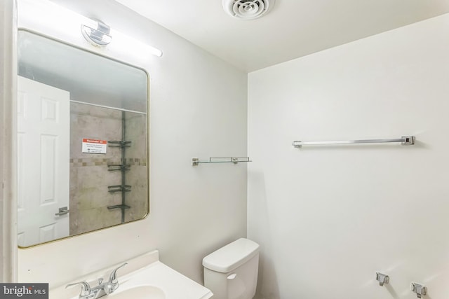 bathroom featuring toilet, a shower, and vanity