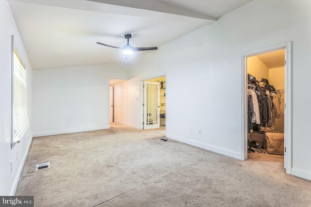 unfurnished bedroom with a walk in closet, carpet flooring, lofted ceiling, a closet, and baseboards