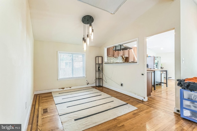 dining area with light wood-type flooring, lofted ceiling, and baseboards