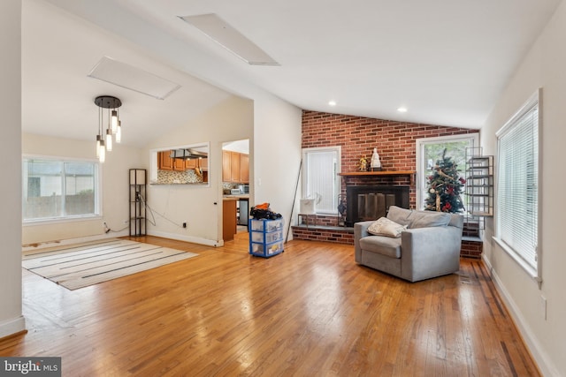 living room with vaulted ceiling, healthy amount of natural light, light wood-type flooring, and baseboards