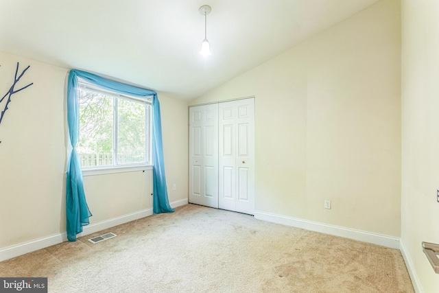unfurnished bedroom with carpet floors, vaulted ceiling, a closet, and baseboards