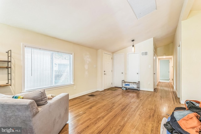 living area with light wood-type flooring, vaulted ceiling, and baseboards