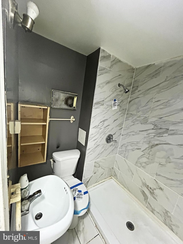 full bath with marble finish floors, a stall shower, a sink, and toilet