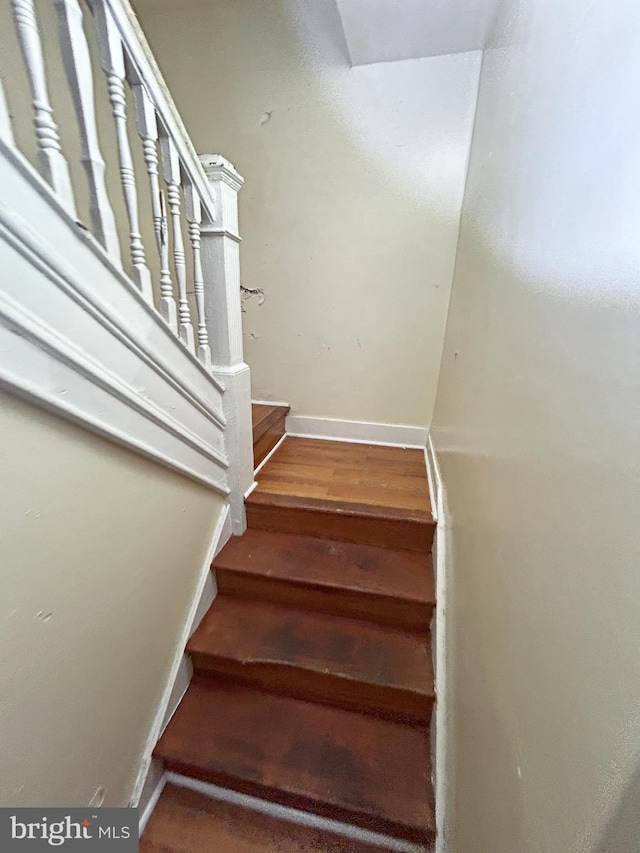 stairs featuring wood finished floors and baseboards