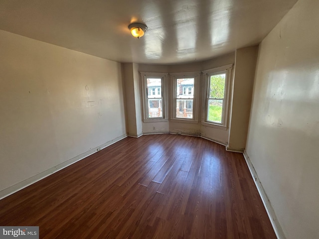 spare room featuring dark wood finished floors and baseboards