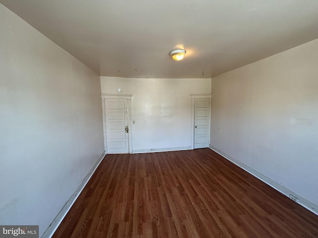 spare room featuring baseboards and dark wood-style flooring
